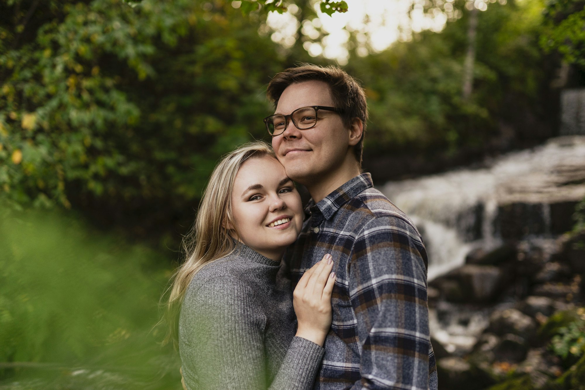 A couple standing together outdoors, smiling at the camera