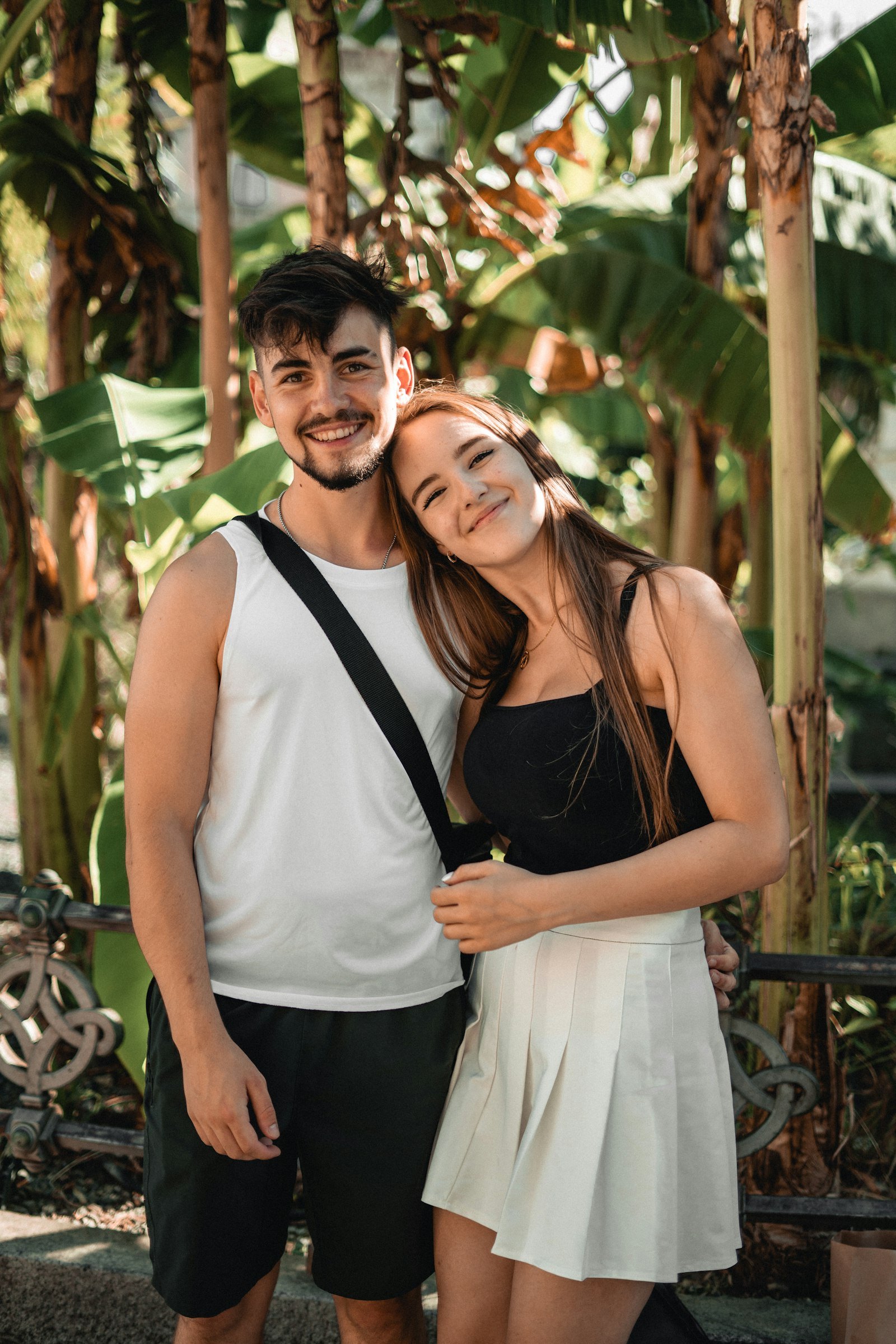 A young couple standing together outdoors, smiling at the camera
